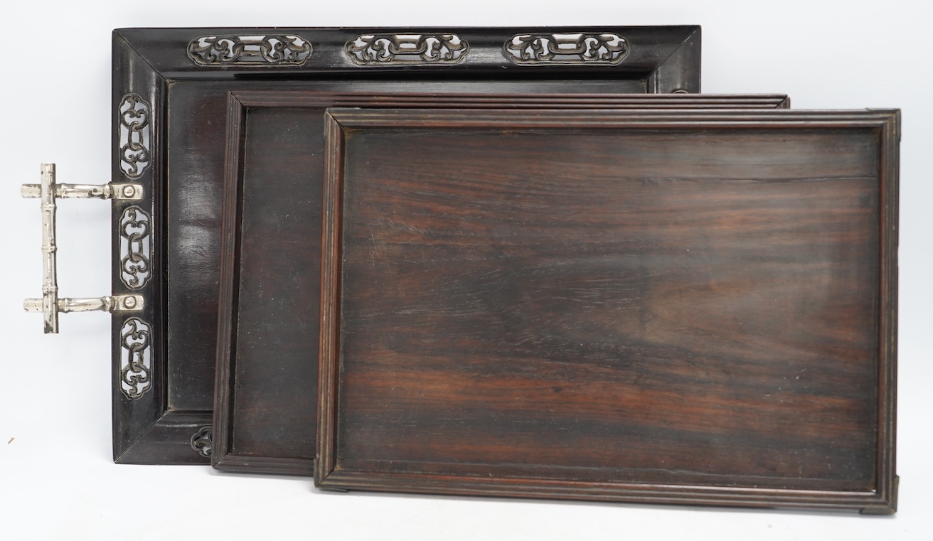 Three 19th century Chinese hongmu or zitan trays, one with silver handles, largest 48cm. Condition - fair